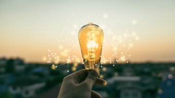 Hand hält leuchtende Glühbirne in die Luft | © sommart - stock.adobe.com